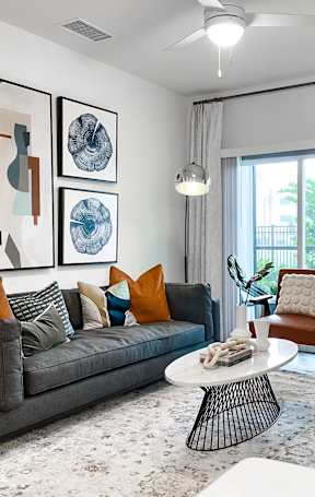 A living room with a grey couch, a coffee table, and a painting on the wall.